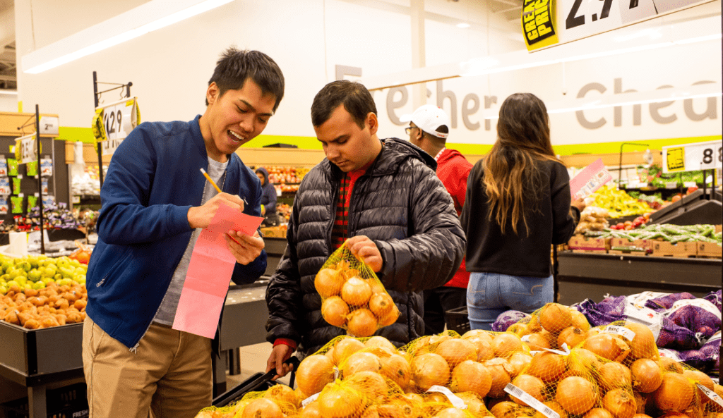 volunteer helping young man at the grocery store picking out produce. 