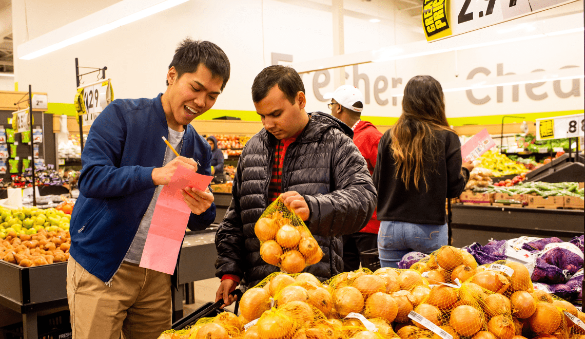 volunteer helping young man at the grocery store picking out produce.