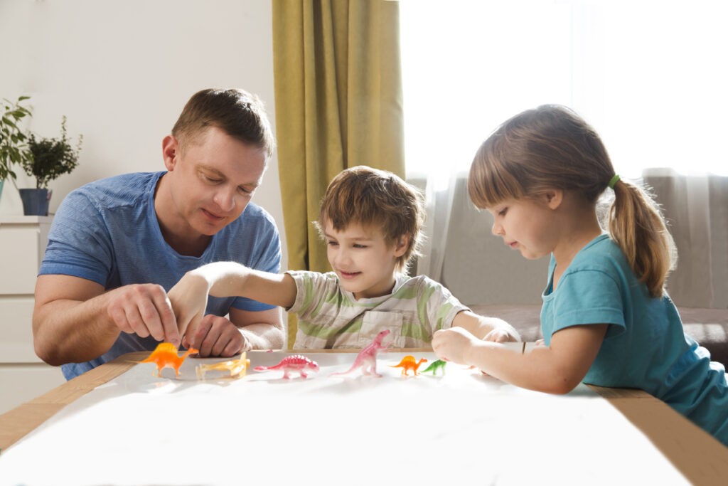 Dad with two kids  playing animal figures together at home. Family having fun playing at home. 