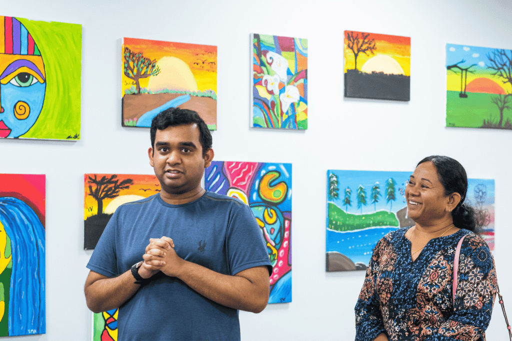 Art student standing in front of their painting with caregiver smiling lovingly