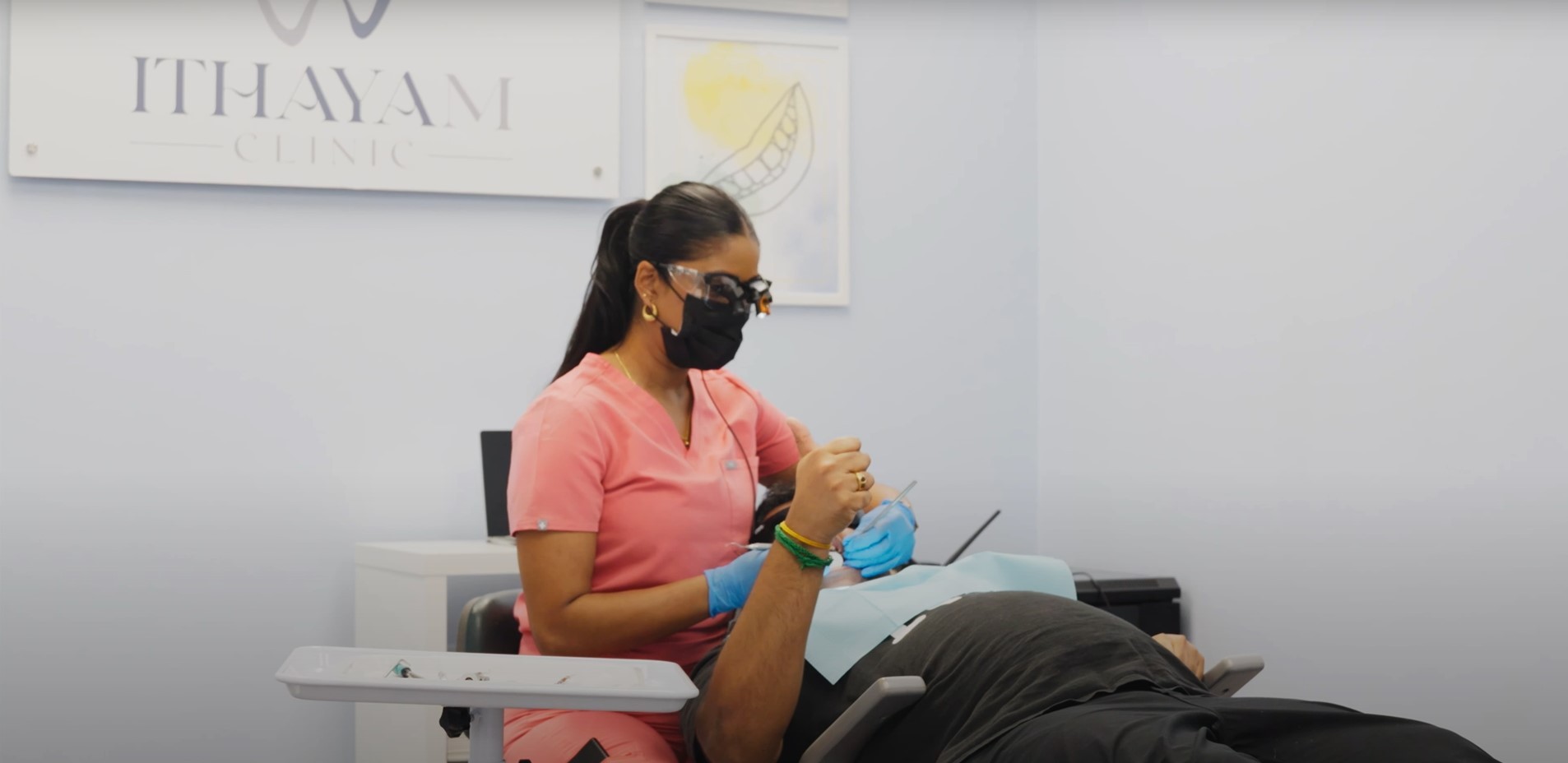 Image of a dental hygienist in pink scrubs and protective gear providing dental care to a patient at Ithayam Clinic, a clinic dedicated to inclusive and compassionate dental services for the autistic community.