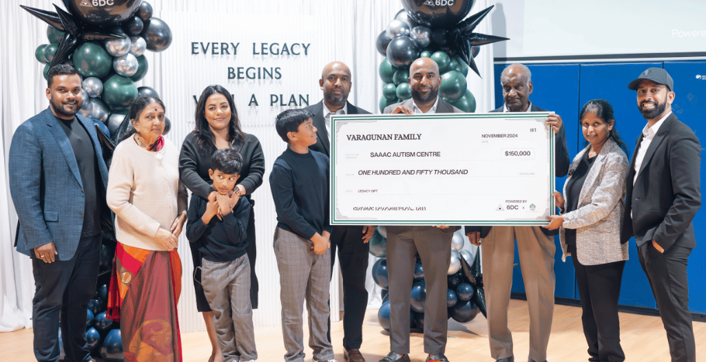 Group photo featuring the Varagunan family presenting a ceremonial check for $150,000 to the SAAAC Autism Centre as part of a legacy gift initiative. The backdrop includes a decorative balloon arrangement and the words 'Every Legacy Begins with a Plan.' The group is composed of family members and representatives from the SAAAC Autism Centre, highlighting a significant moment of generosity and community support.