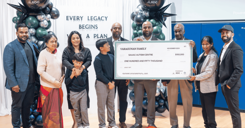 Group photo featuring the Varagunan family presenting a ceremonial check for $150,000 to the SAAAC Autism Centre as part of a legacy gift initiative. The backdrop includes a decorative balloon arrangement and the words 'Every Legacy Begins with a Plan.' The group is composed of family members and representatives from the SAAAC Autism Centre, 6DC Consulting, and Wealthbridge, highlighting a significant moment of generosity and community support.