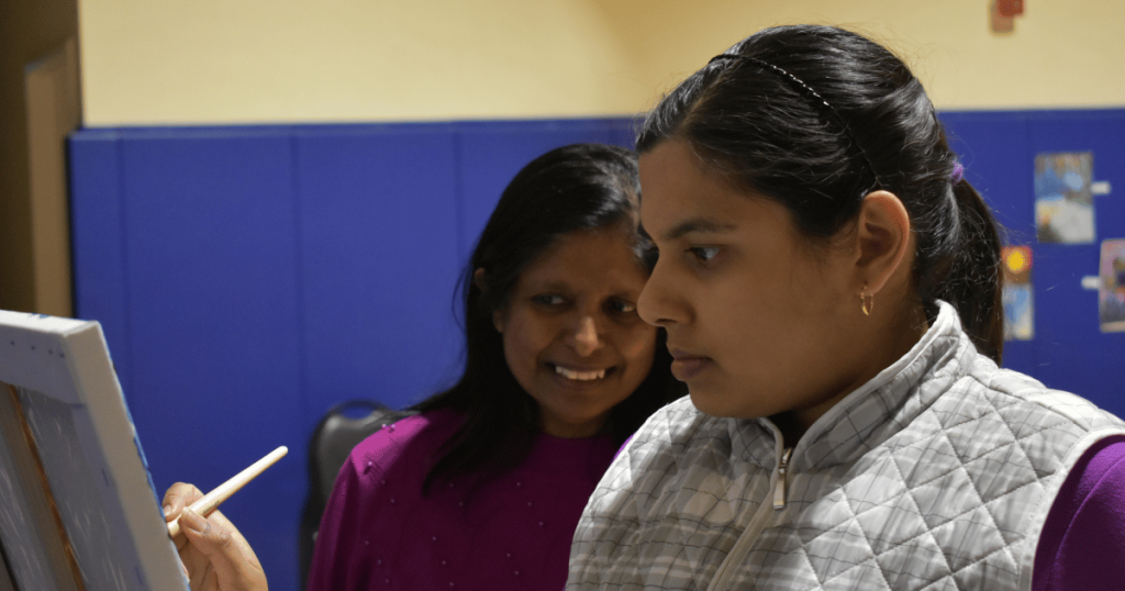 Geetha Moorthy, Founder and CEO of SAAAC Autism Centre, watching a student paint during a sensory-informed autism arts program in Scarborough.
