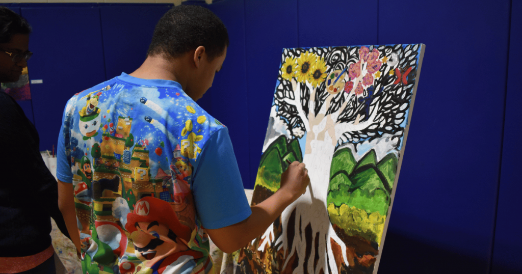 An autistic youth painting a canvas during a sensory-informed arts program at SAAAC Autism Centre in Scarborough, supported by Ontario Trillium Foundation funding.