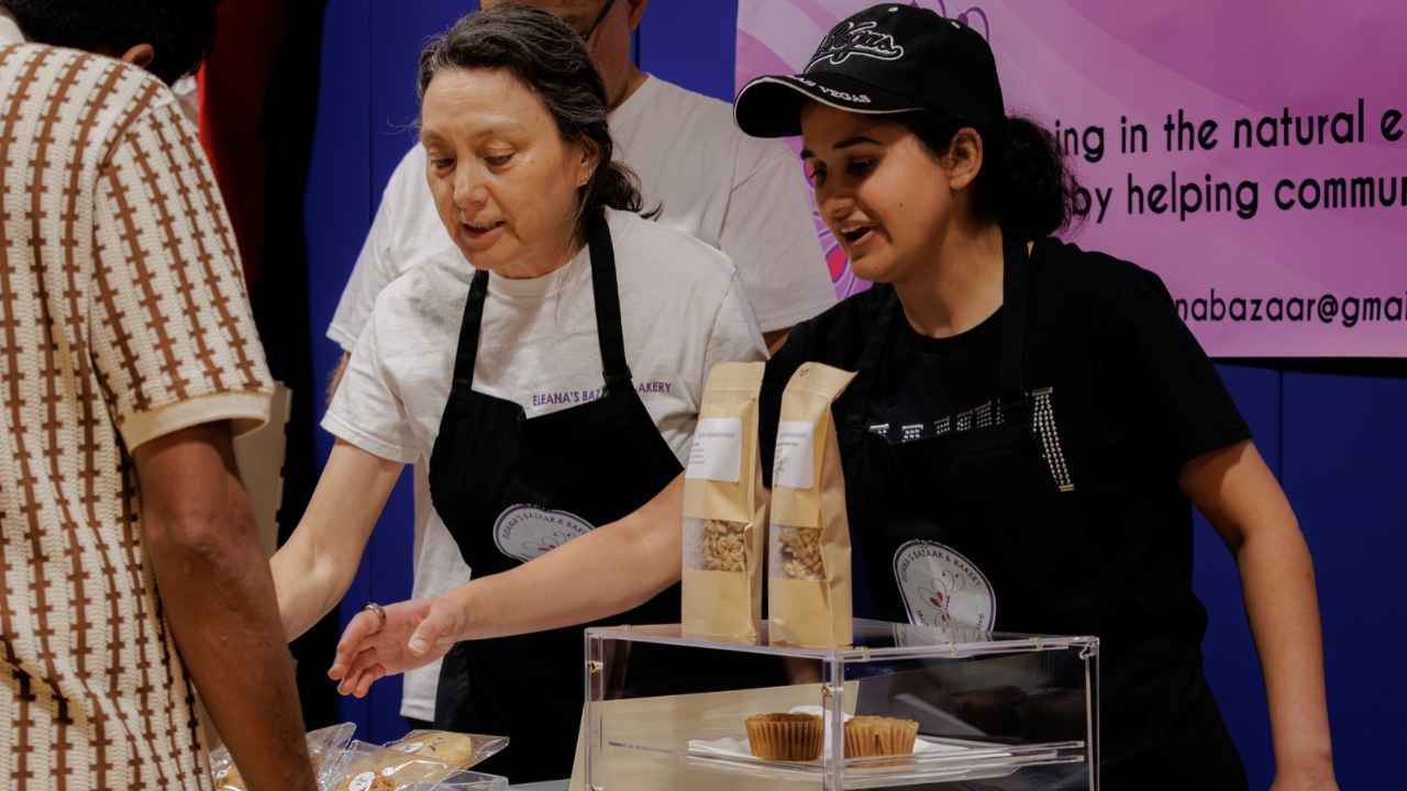 Two SPARKS entrepreneurs showcasing baked goods from their business to a visitor during SAAAC’s SPARKS Demo Day.